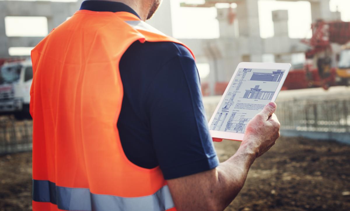 Man on building site holding ipad.
