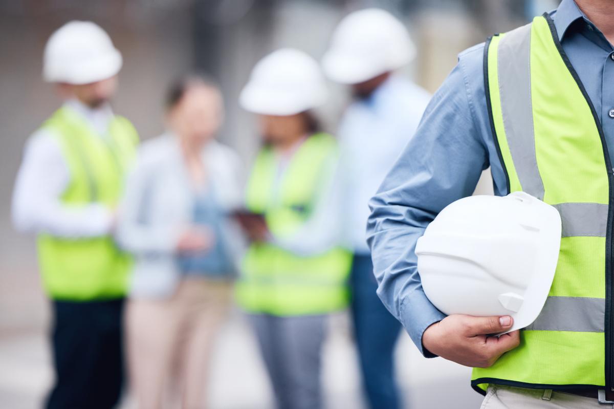 Man Carrying Helmet with Group in Background