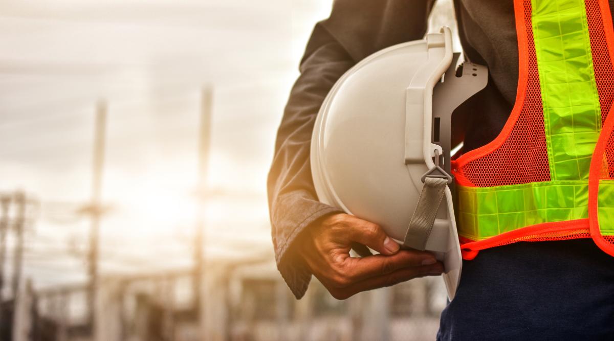 Man on construction site holding hat