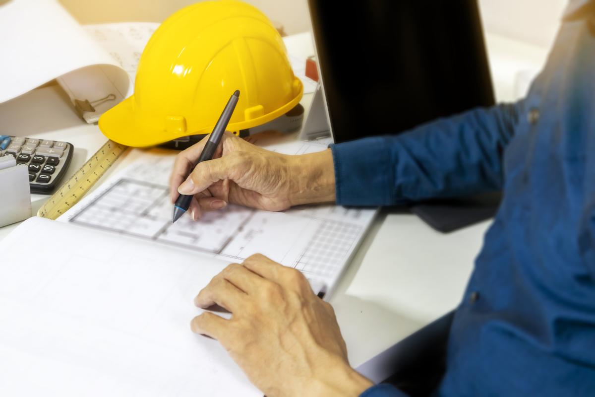 Picture of a safety hat in background with person writing next to it